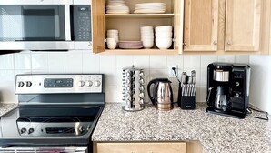 Une cuisine équipée d’un four à micro-ondes, d’une cuisinière, d’une machine à café et d’un meuble contenant de la vaisselle.