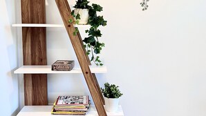 Une bibliothèque blanche avec une échelle en bois, diverses plantes et des livres.