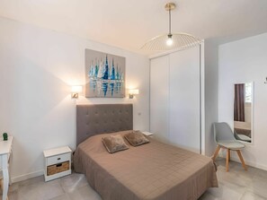 Un dormitorio moderno con una cama grande, una mesita de noche, una silla y un cuadro en la pared.