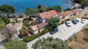 A coastal property with a parking area, a small building with a tiled roof, and a view of the sea. - Cosy apartment in villa for 4 people with A/C, WIFI and TV (Solenzara)