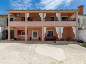 A two-story building with a balcony on the upper floor, a door with a window on the ground floor, and a small outdoor seating area. - Villa Mate i Kate by Interhome (Rovinj/Žminj)