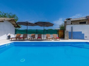 A swimming pool with six wooden lounge chairs and two umbrellas. - Villa Mate i Kate by Interhome (Rovinj/Žminj)