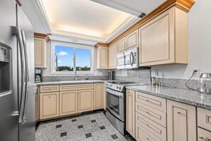 Enjoy cooking in this well-equipped kitchen with a stainless steel refrigerator, oven, and microwave.