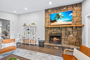Cozy living room with a fireplace, flat-screen TV, and comfortable seating areas.