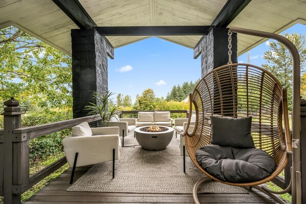 Relax in a serene outdoor space with a fire pit, surrounded by lush greenery and comfortable seating.