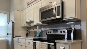 A kitchen with white cabinets, a stainless steel microwave, a stove, and a dishwasher.