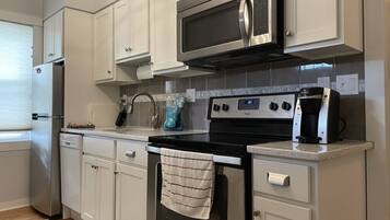 A kitchen with white cabinets, a stainless steel microwave, a stove, and a dishwasher.