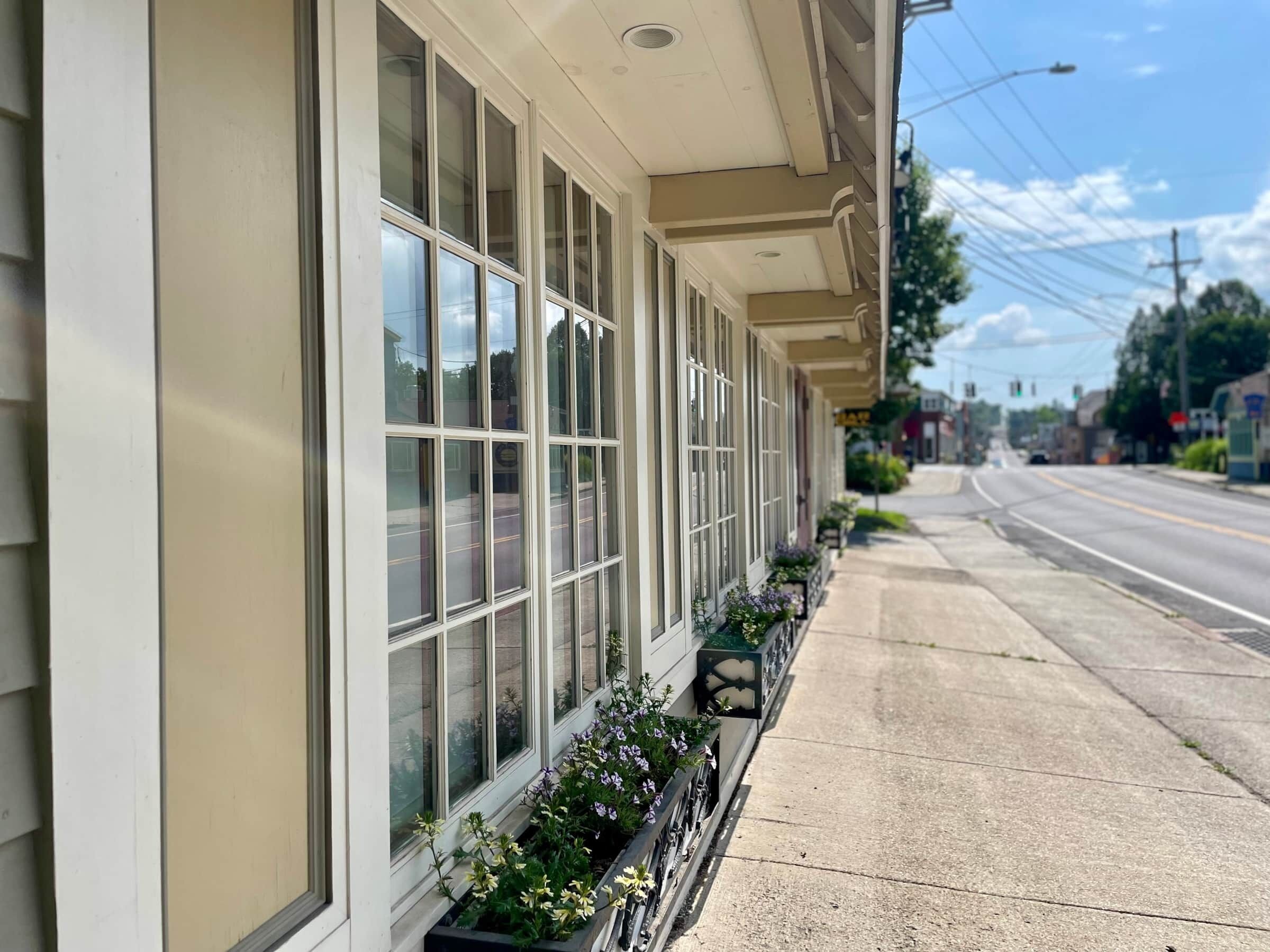 A building with large windows and a row of flower boxes along the sidewalk.