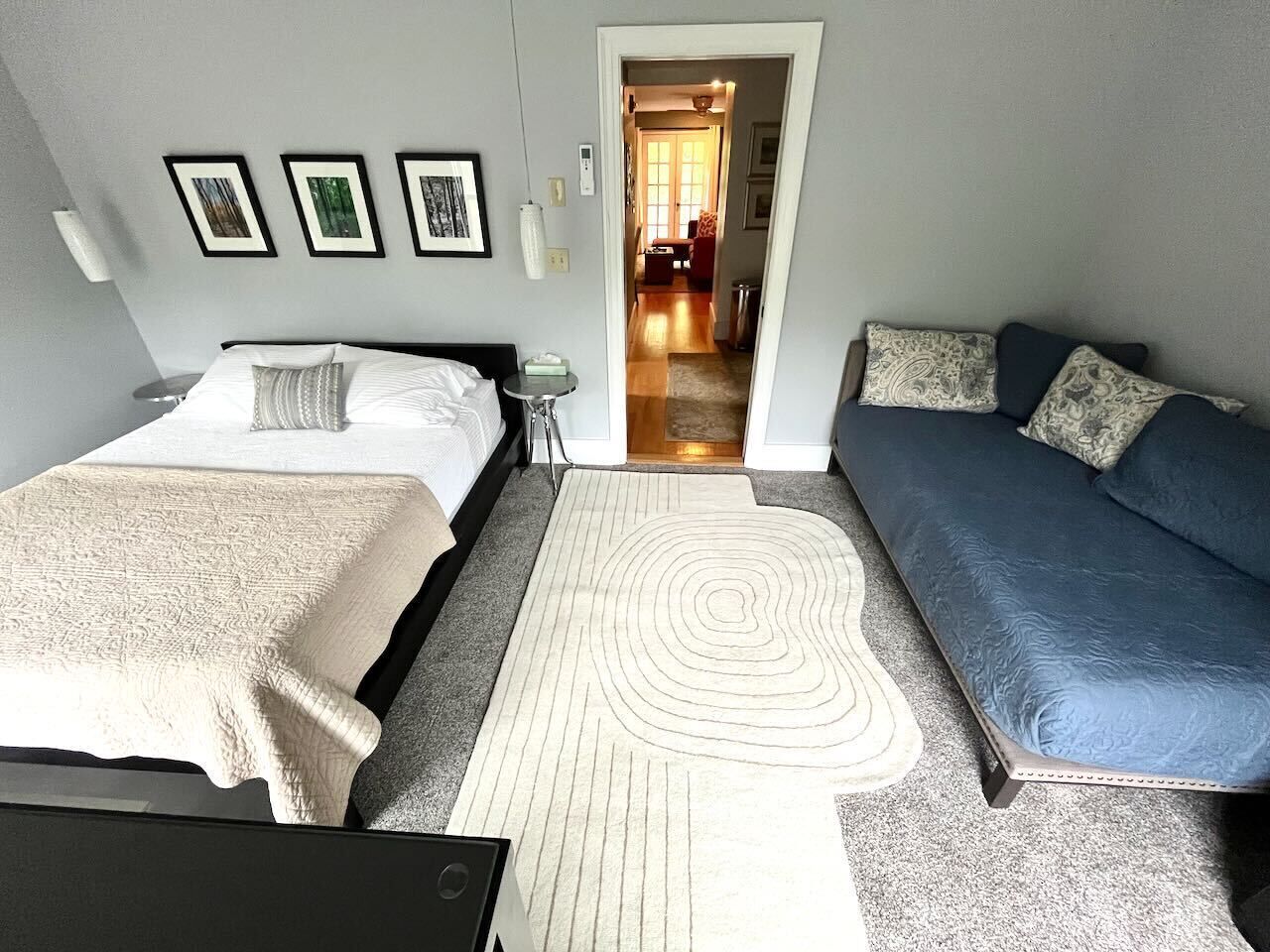 Une chambre avec deux lits, un canapé, une table de chevet et un tapis à motifs.