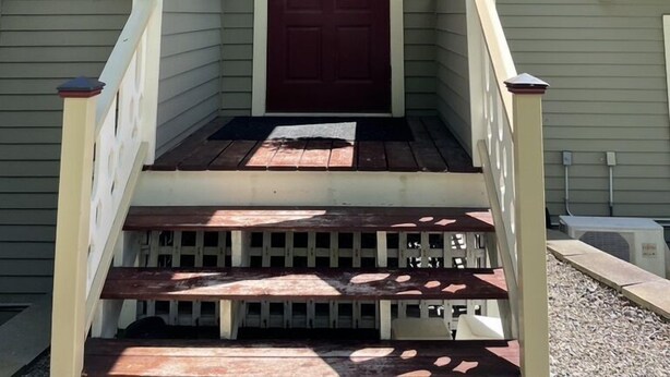 Ett hus med en veranda framför, en röd dörr och en liten balkong.