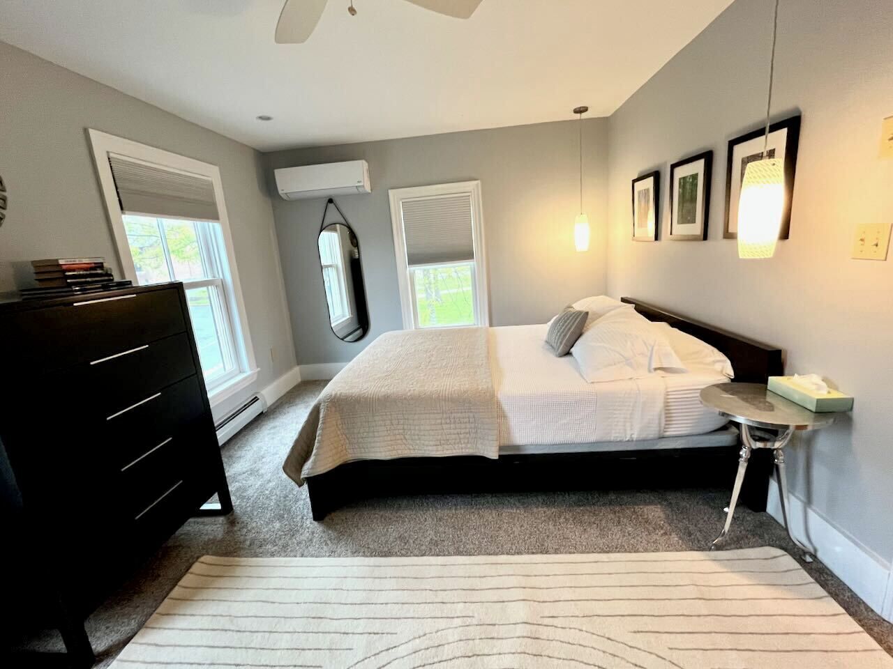 A bedroom with a bed, dresser, bedside table, and a window.