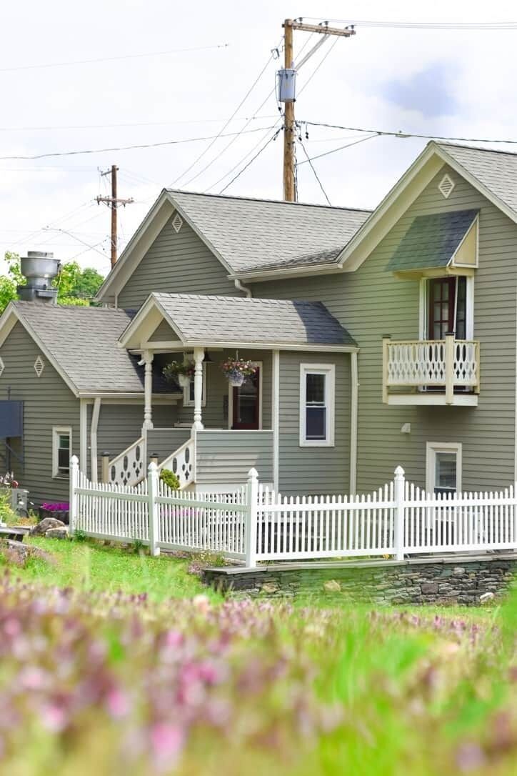 A two-story house with a porch and a white picket fence.