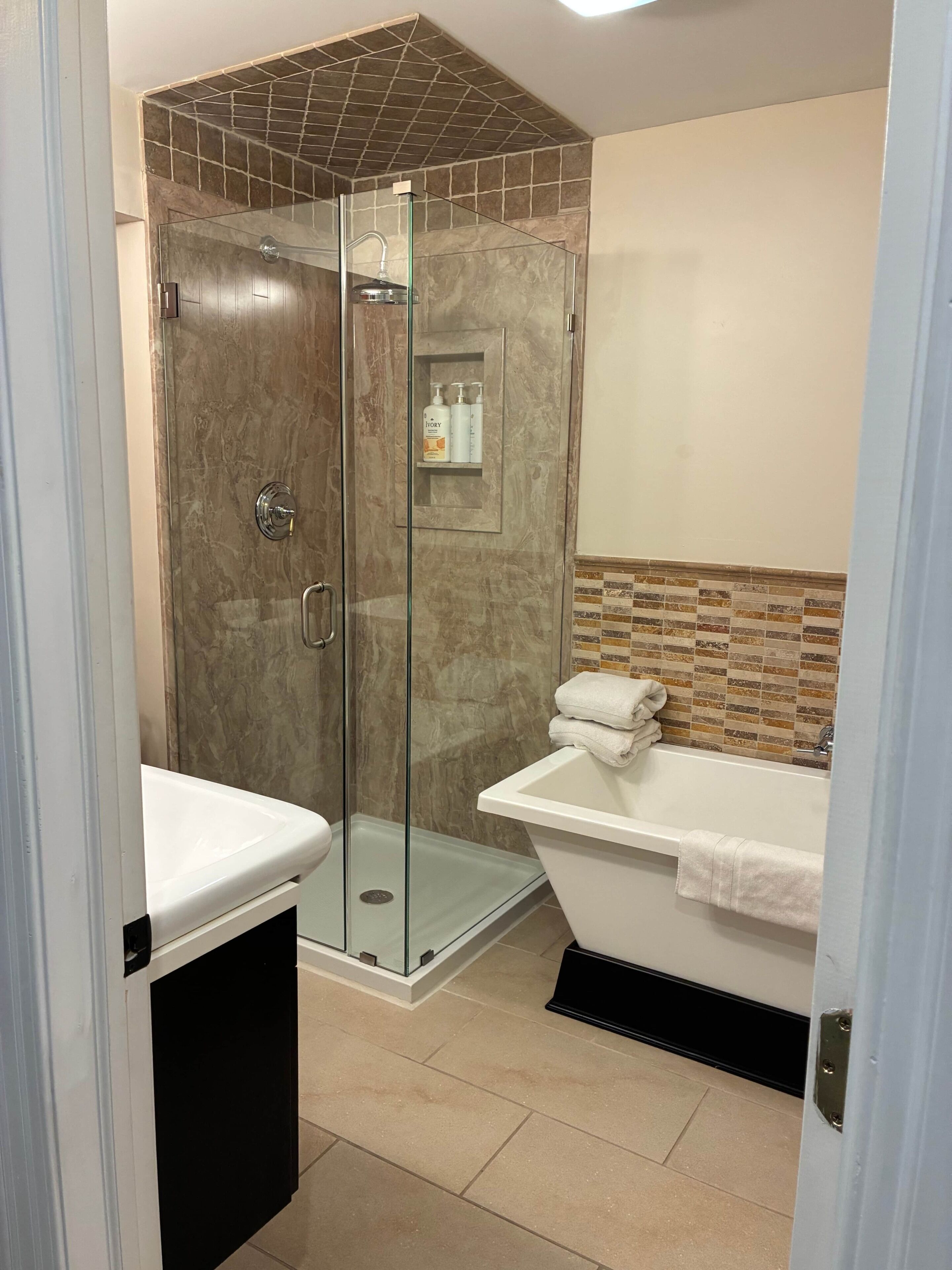 A bathroom with a glass-enclosed shower, a bathtub, and a vanity with a mirror.