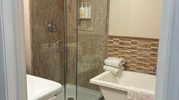 A bathroom with a glass-enclosed shower, a bathtub, and a vanity with a mirror.