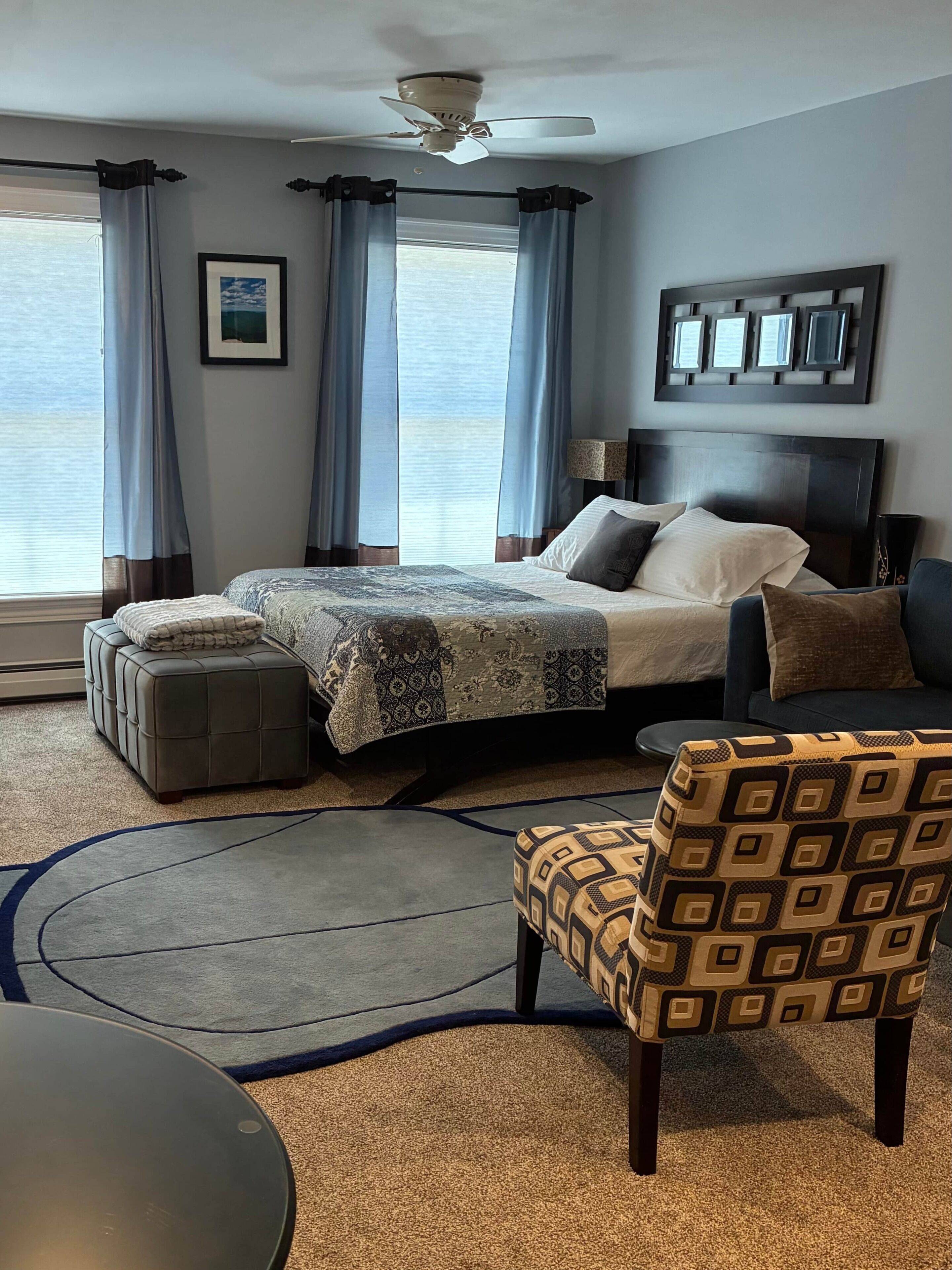 Une chambre d’hôtel équipée d’un lit, d’un canapé, d’une chaise, d’un ventilateur de plafond et offrant une vue sur la mer.