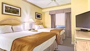 A hotel room with two beds, a television, and a ceiling fan.