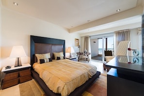 Quarto de hotel com cama grande, escrivaninha, cadeira e vista para o exterior.
