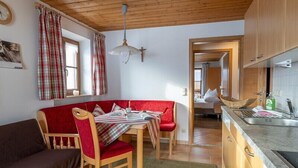 Tunnelmallinen huone, jossa on ruokapöytä, punainen sohva, puinen katto ja näkymä keittiöön.