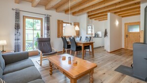Un salón espacioso con una mesa de comedor de madera, un sofá gris y una cocina con estufa.
