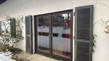 Ein Haus mit einer Schiebetür, ein kleiner Garten mit einer Pflanze und ein mit Schnee bedeckter Boden.