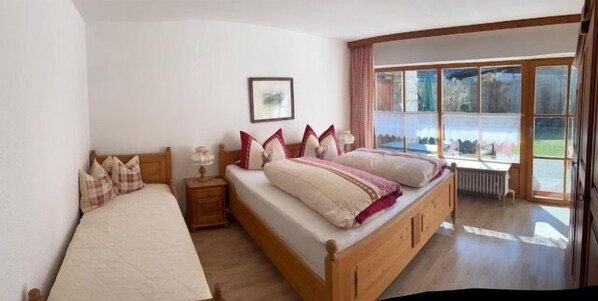 A bedroom with two beds, a window, and a radiator.
