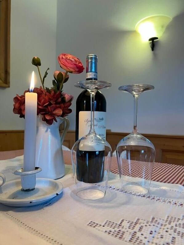 Une table avec une bougie allumée, une bouteille de vin et deux verres à vin, le tout posé sur une nappe.