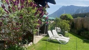 A backyard with a lawn, a tree with purple flowers, and a white fence. - Vacation apartment Kienberg for 2 persons, 45 sqm, eat-in kitchen, with balcony (Inzell)