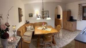 A cozy kitchen with a dining table, wooden cabinets, and a stone floor. - Vacation apartment Kienberg for 2 persons, 45 sqm, eat-in kitchen, with balcony (Inzell)