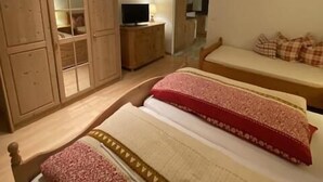 A bedroom with two beds, a TV, wooden furniture, and a deer head decoration. - Vacation apartment Kienberg for 2 persons, 45 sqm, eat-in kitchen, with balcony (Inzell)