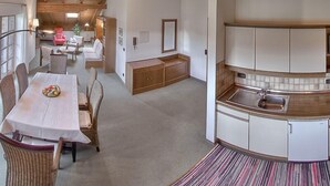 A spacious living area with a dining table, chairs, and a kitchen with white cabinets and a tiled backsplash. - Vacation apartment 9 for 4 people in the attic, 2 bedrooms, balcony, 82 m² (Inzell)
