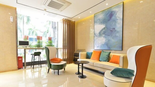A modern hotel room with a sofa, chairs, a desk, and a large abstract painting on the wall. - City Comfort Inn (Zhuhai Qinglv Middle Road) (Zhuhai)