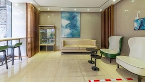 A modern lobby with a sofa, chairs, a small table, and a glass display cabinet. - City Comfort Inn (Zhuhai Qinglv Middle Road) (Zhuhai)