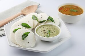 Un plato de idlis, un tazón de chutney y un tazón de sopa.
