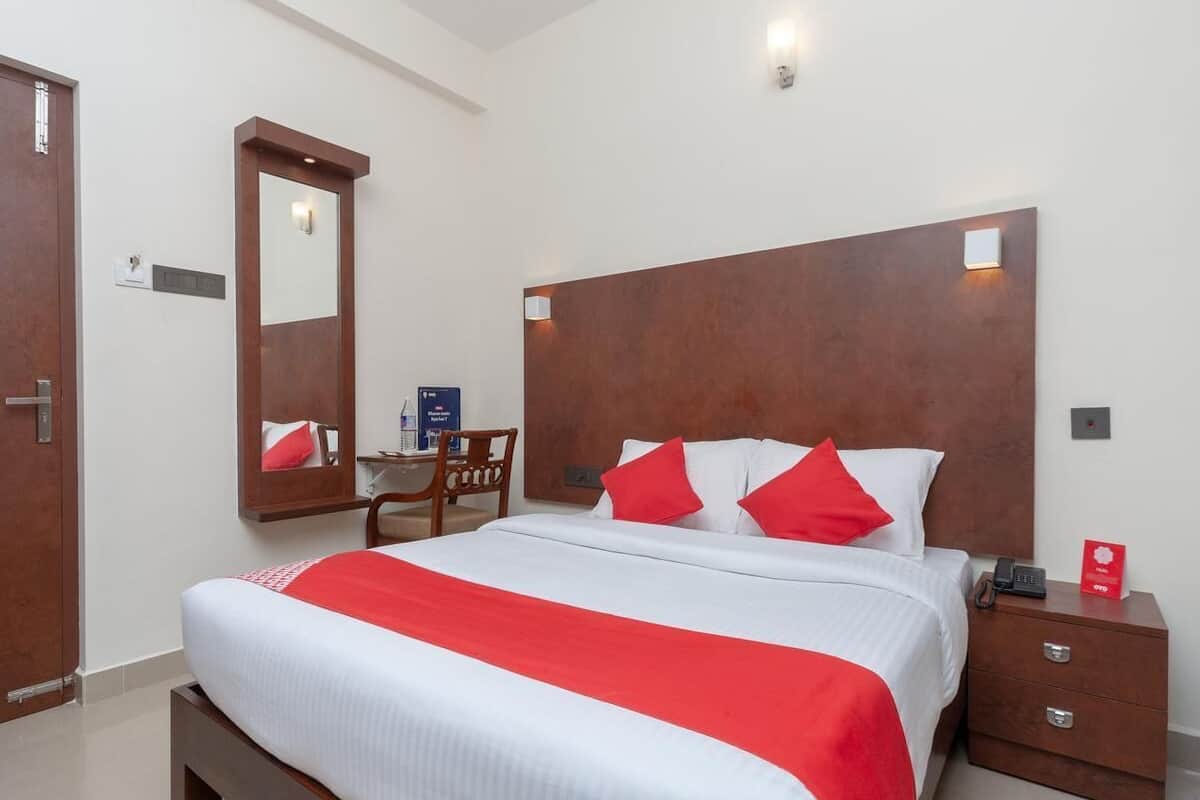 Une chambre d’hôtel avec un grand lit, une tête de lit en bois, une table de chevet avec un téléphone et un bureau avec une chaise.