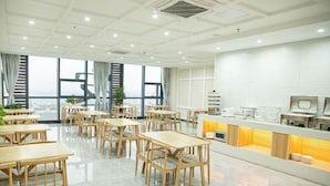 A spacious dining area with wooden tables and chairs, large windows, and a counter with a display of items. - Shankee Tea Style Hotel (Danyang Economic Development Zone) (Danyang)