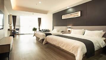 A modern hotel room with a large bed, a desk, and a view of the outdoors.