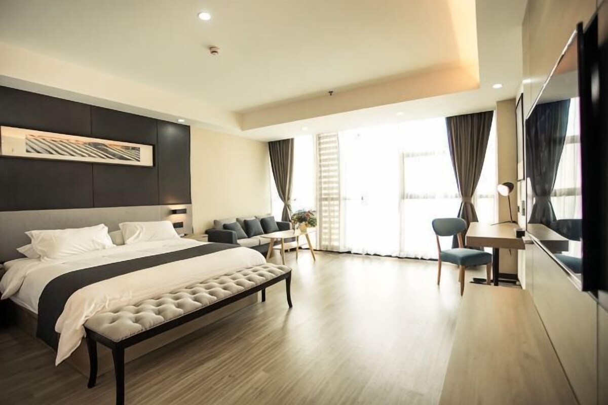 A modern hotel room with a large bed, a desk, and a seating area.