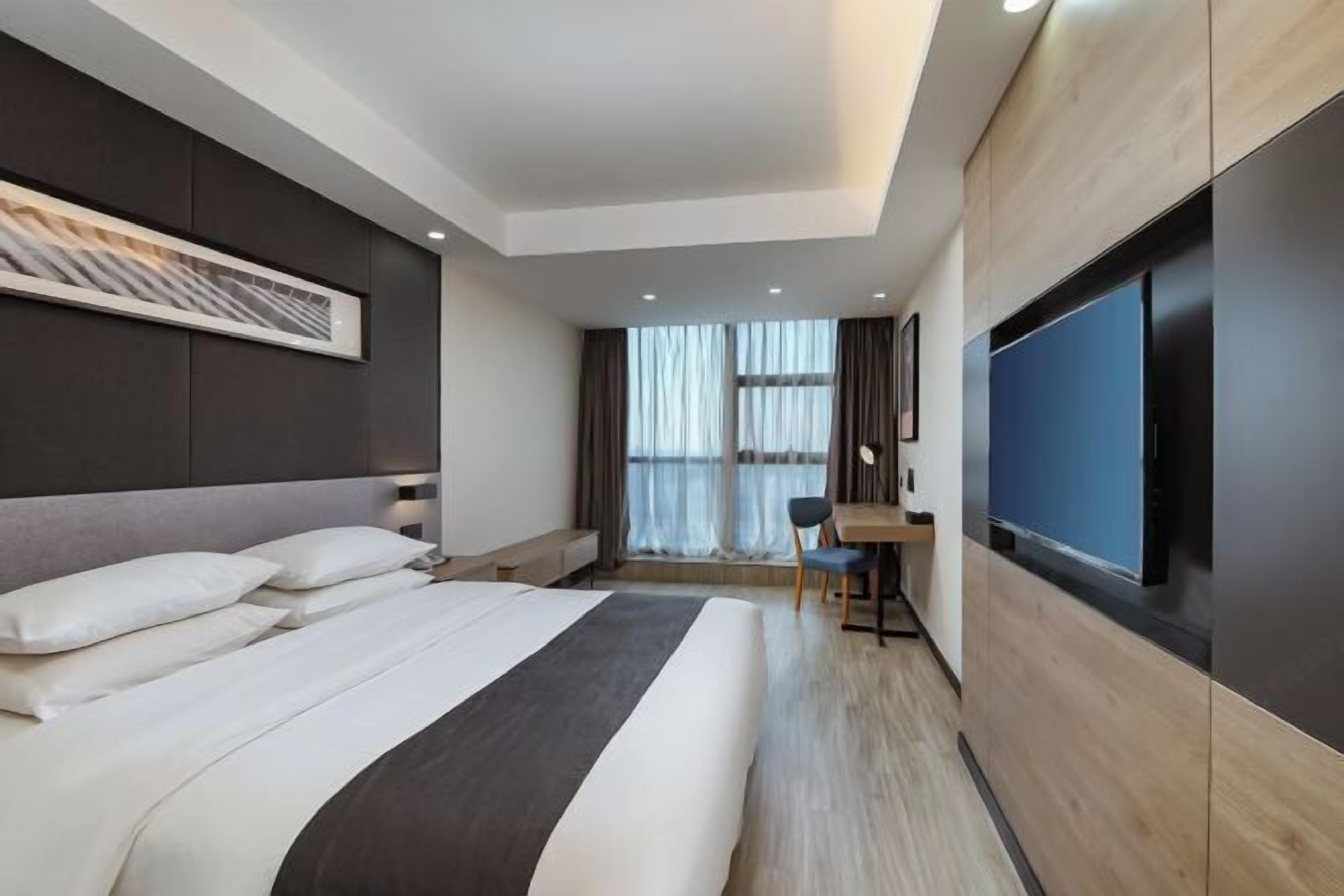 Una habitación de hotel moderna con una cama grande, un escritorio y una televisión.