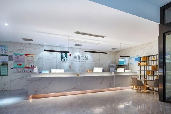 A hotel reception area with a marble reception desk, a digital screen, and a seating area with a small table and chairs. - Shankee Tea Style Hotel (Danyang Economic Development Zone) (Danyang)