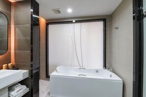 Un baño moderno con una bañera grande, un tocador con espejo y un perchero para toallas.