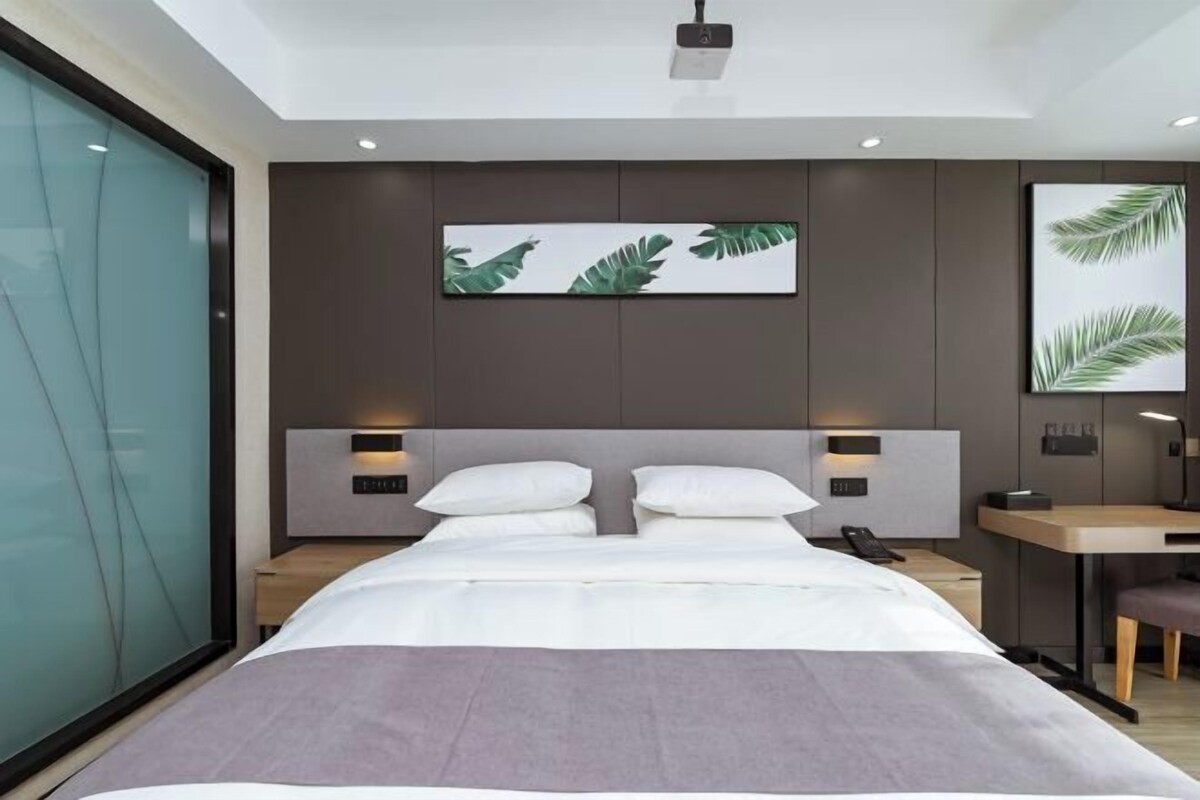 Un dormitorio moderno con cama, mesitas de noche, escritorio y obras de arte en las paredes.