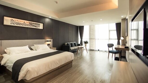 A modern hotel room with a large bed, a desk, a chair, and a sofa. - Shankee Tea Style Hotel (Danyang Economic Development Zone) (Danyang)