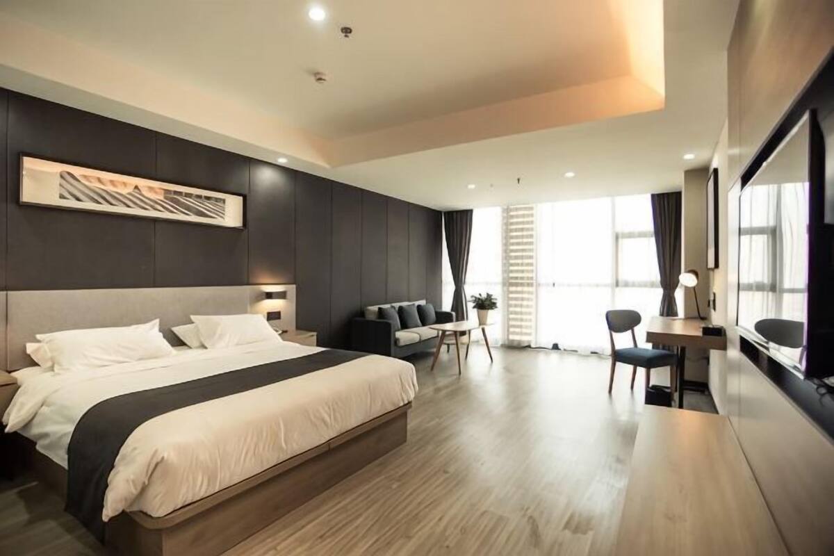 Una habitación de hotel moderna con una cama grande, un escritorio, una silla y un sofá.