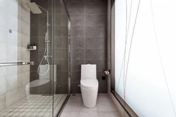 Un baño moderno con ducha de vidrio, inodoro y piso de baldosas.