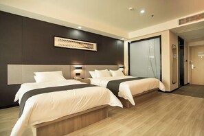 Habitación de hotel moderna con dos camas, una obra de arte grande en la pared y un armario con puerta corredera.