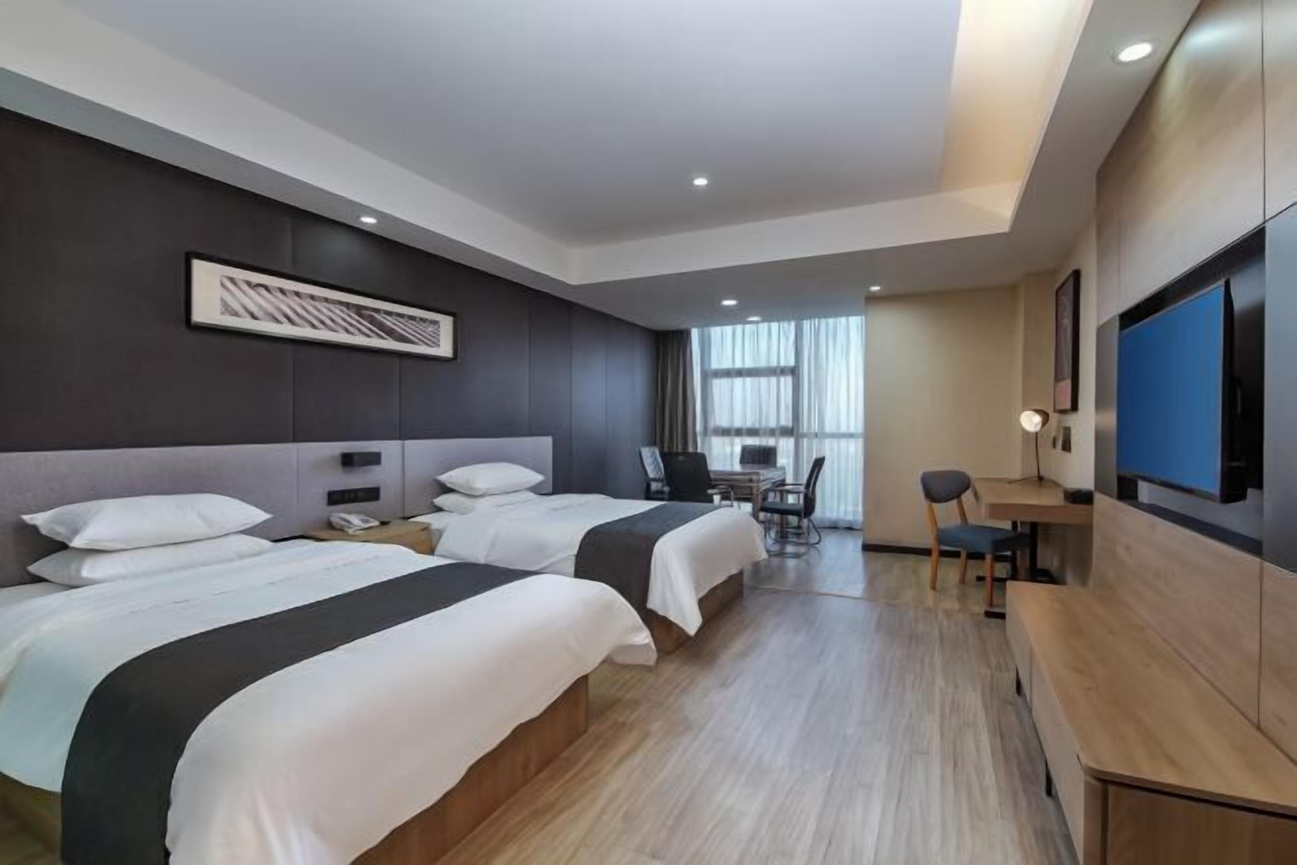 A hotel room with two beds, a desk, a chair, a TV, and a window with curtains.