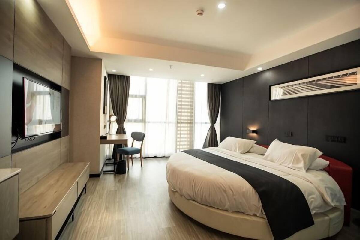 Una habitación de hotel moderna con cama, escritorio, silla y televisor.