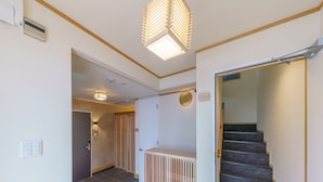 A modern interior with a staircase, a radiator, and a door leading to another room. - Yadoya Fukurou (Tokyo)