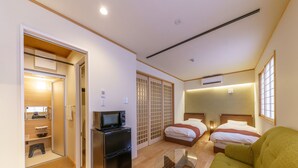 A hotel room with a kitchenette, a bed, a green sofa, and a sliding door closet. - Yadoya Fukurou (Tokyo)