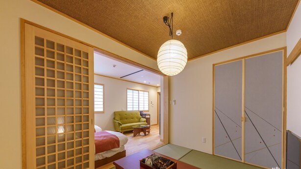 A traditional Japanese room with tatami flooring, a low wooden table, a green sofa, and sliding doors. - Yadoya Fukurou (Tokyo)